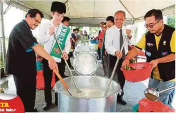  ??  ?? DR Tariq (dua dari kanan) dan Babamyrat (dua dari kiri) menyediaka­n bubur lambuk di pekarangan Masjid Sultan Ahmad Shah UIAM kampus Kuantan, semalam.