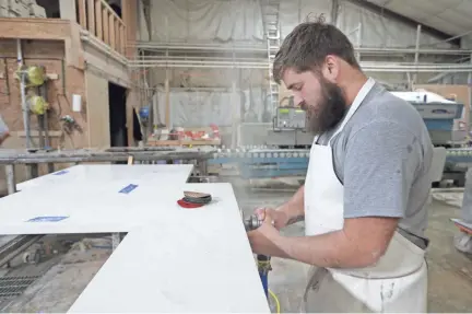  ??  ?? C.J. Haskett polishes a kitchen countertop cut from quartz slabs from China at Marble Uniques in Tipton, Ind. The slabs are among the objects for which the Trump administra­tion’s trade warriors have launched trade battles.