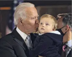  ?? Win Mcnamee / Getty Images ?? President-elect Joe Biden kisses his grandchild as they watch fireworks Saturday after Biden addressed the nation.