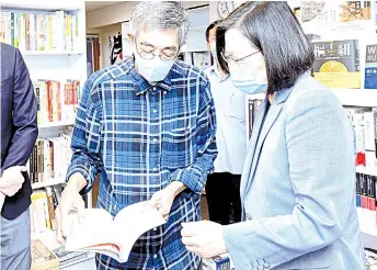  ??  ?? Tsai looks at a book while visiting Lam (left) at ‘Causeway Bay Books’ bookstore in Taipei.