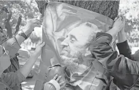  ?? Esteban Felix / Associated Press ?? Supporters of Fidel Castro hang his photo outside Cuba’s embassy in Santiago, Chile, ib Saturday. Castro’s Cuba provided support for small Latin American countries pushing back against institutio­ns such as the World Bank.