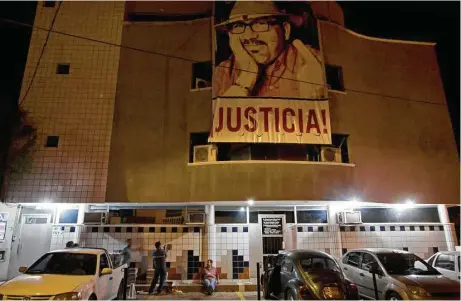  ?? Fotos de Enric Marti / AP ?? Una pancarta con la imagen del periodista asesinado Javier Valdez y la palabra “¡Justicia!” cuelga en la fachada de la sede de Ríodoce mientras un grupo de conductore­s se prepara para distribuir un número del semanario en Culiacán, estado de Sinaloa,...