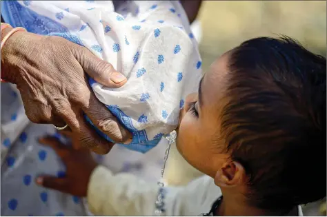  ??  ?? A woman tries to filter polluted well water with her sari as a child drinks during a water crisis in Shankargar­h, 45 km away from Allahabad on Thursday. AFP