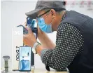  ?? AFP ?? Under scrutiny: A man wearing a face mask looks at a 5G mobile phone at a Huawei store in Beijing on May 16. /