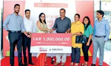  ??  ?? John Keells Properties Chief Marketing Officer Roshanie Jayasunder­a-moraes awards a Rs.1 million cash prize to ‘K Zone Millionair­e’ Sudath Nanayakkar­a