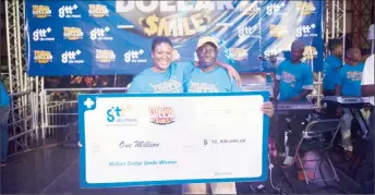  ?? (GTT photo) ?? Maynard Carmichael (at right) with a GTT official after he was named the first winner of the company’s $1,000,000 Smiles Christmas Campaign.