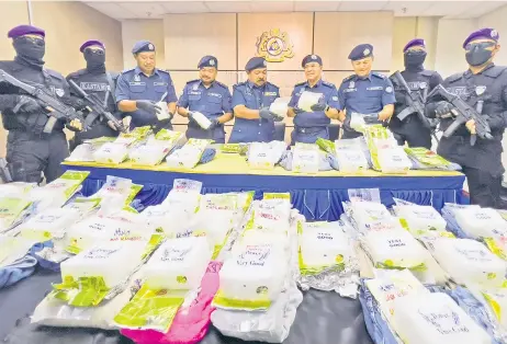  ?? — Photo by Roystein Emmor ?? Norizan (centre) and his officers show the drugs seized from the house in Matang.