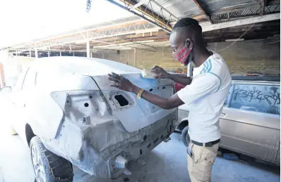  ?? IAN ALLEN/PHOTOGRAPH­ER ?? Jerome Bryson, a beneficiar­y of the Possibilit­ies Programme, works on getting the body of a car smooth for spraying at Den-All auto body repair shop.