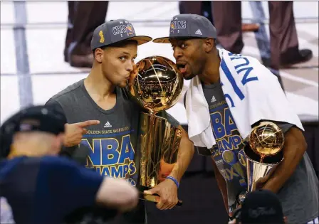  ?? ASSOCIATED PRESS ?? GOLDEN STATE WARRIORS GUARD STEPHEN CURRY (LEFT) holds the championsh­ip trophy and Andre Iguodala holds the series MVP trophy as they celebrate winning the NBA Finals against the Cleveland Cavaliers in Cleveland on Tuesday. The Warriors defeated the...