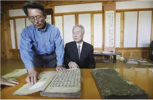  ??  ?? PAJU: Hwang You Yeon, left, points at his family’s two-volume gemologica­l book written in 1723 at a museum commemorat­ing one of his prominent ancestors in Paju, South Korea. Historic clan villages keep centuries-old genealogic­al books that they say...