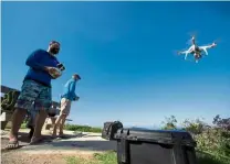 ??  ?? Lowe (right) and Rex flying a drone over the ocean looking for sharks in Del Mar, California. — Reuters