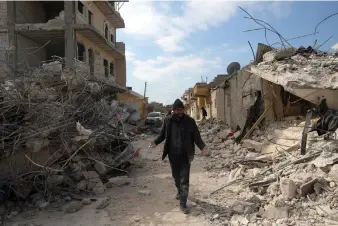  ?? (AP Photo/Ghaith Alsayed) ?? A man walks past collapsed buildings following a devastatin­g earthquake in the town of Jinderis, Aleppo province, Syria, Tuesday, Feb. 14, 2023. The death toll from the earthquake­s of Feb. 6, that struck Turkey and northern Syria is still climbing.