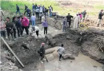  ??  ?? Excavation workers had to pump water out of the flooded pit before they could retrieve pieces of the bigger statue on Wednesday.