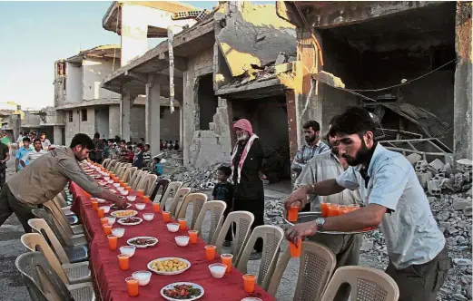  ?? — AFP ?? Communal
iftar: Volunteer servers laying out the table for Douma townfolk to break fast together.