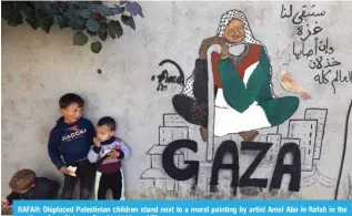  ?? — AFP ?? RAFAH: Displaced Palestinia­n children stand next to a mural painting by artist Amal Abo in Rafah in the southern Gaza Strip, on Dec 31, 2023.