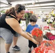  ?? Al Seib Los Angeles Times ?? CLAUDIA ZAVALA helps her nephew Thiago Zavala, 4, pick flowers this week at the 104-year-old market, part of the larger L.A. f lower district.