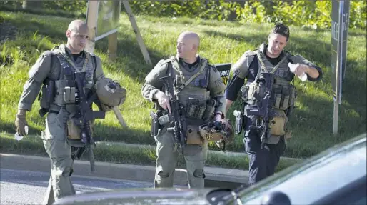  ?? Jose Luis Magana/Associated Press ?? Heavily armed police officers patrol Thursday outside a newspaper office in Annapolis, Md., where a gunman killed five people. Police had a suspect in custody.