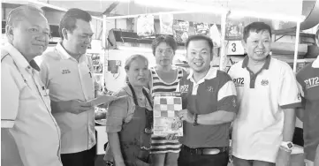  ??  ?? Chan (fifth left) presenting a calendar to one of the hawkers. Also seen is Tan (second left).