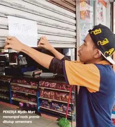  ??  ?? PEKERJA Mydin Mart menampal notis premis ditutup sementara.