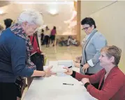  ??  ?? Latus, right, signs a book for Angela Weaver, of Del City.