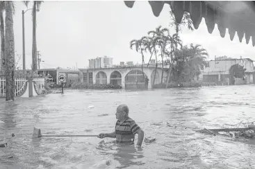  ?? Marie D. De Jesús / Houston Chronicle ?? Maximilian­o Encarnacio­n uses a broom to push away debris carried by the floodwater­s caused by torrential rains on Oct. 8 in San Juan, 18 days after Hurricane Maria touched down in Puerto Rico.