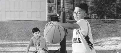  ?? ANDREA K. MCDANIELS/BALTIMORE SUN ?? Khasan Al-Mateen dribbles a basketball while his friend Cooper Chasm takes a break while playing.