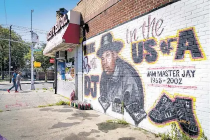  ?? AP PHOTOS ?? Pedestrian­s pass a mural, by artist Art1Airbru­sh, of rap pioneer Jam Master Jay in the Queens borough of New York.