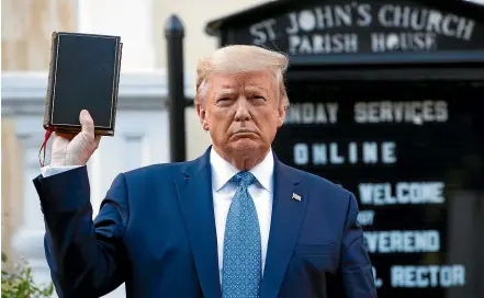  ?? AP ?? Donald Trump waves a Bible as he makes a heavily guarded visit toe St John’s Church across Lafayette Park from the White House.