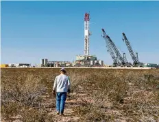  ?? — Reuters ?? Risky work:
An oil worker walking towards a drill rig after placing groundmoni­toring equipment in the vicinity in Loving County, Texas.