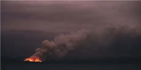  ??  ?? A fire in the distance seen from the Royal Australian Navy’s HMAS Adelaide ship off the coast in Eden in New South Wales, as part of bushfire relief operations.