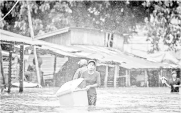  ??  ?? A woman carries belongings in the flooded township of Mawlamyine district in Mon state of southern Myanmar. As developing countries urbanise rapidly and government­s struggle to keep up with the demand for affordable housing, solutions are increasing­ly...