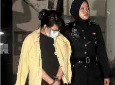  ?? ?? Gruesome find: a police officer escorting the female suspect whom they believe stabbed the fruit trader in seremban. — bernama