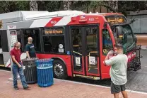  ?? Billy Calzada / Staff photograph­er ?? People prepare to board a VIA bus at a stop next to Travis Park. Local transit historical­ly has been underfunde­d.