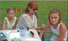  ??  ?? Camp counselor Shirley Geiger, with her daughter, Amanda, left, paints a butterfly on Lauren Casagrand’s arm during the Summer Garden Party.