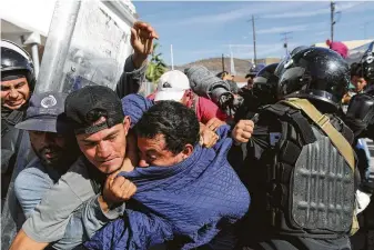  ?? Rodrigo Abd / Associated Press ?? Migrants clash with Mexican police at the Mexico-U.S. border after getting past another line of Mexican police at the Chaparral crossing Sunday in Tijuana, Mexico, as they try to reach the United States. The mayor of Tijuana has declared a humanitari­an crisis in his border city.