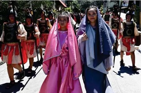  ?? AFP ?? Actors dressed as women of Jerusalem and Roman soldiers walk along a street during the Holy Week celebratio­ns in Manila.