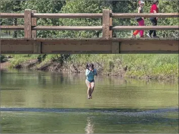  ??  ?? A young woman, above, jumps off Swinging Bridge into the Merced River. People need a reservatio­n to visit the park, even if just going for the day.