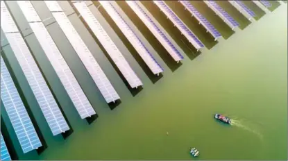  ?? TANG DEHONG / FOR CHINA DAILY ?? Workers in a boat reach a water-based solar farm at Nandang village in Xinghua, a county-level city in Jiangsu province, on Dec 24. China’s solar power industry is expected to have a bigger share in the country’s energy mix this year.