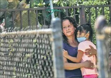  ?? Photograph­s by Francine Orr Los Angeles Times ?? MAGDALENA, who asked that her full name not be used, holds granddaugh­ter Kayla in their yard near the corner of East 27th Street and Stanford Avenue. Residents said they were not told by police to evacuate.