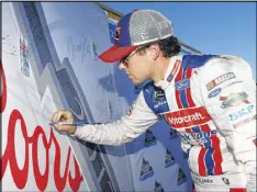  ?? SEAN GARDNER / GETTY IMAGES ?? Ryan Blaney signs a backdrop after qualifying at Kansas. A season-high 11 drivers missed out because their cars didn’t pass inspection­s in time.