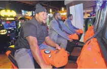  ??  ?? From left, North Texas football players Nick Pichon, Derrick Shaw and Julius Combes race each other on a motorcyle game at Main Event on Wednesday night.