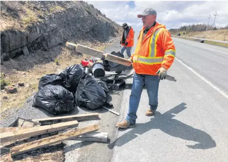  ?? JOE GIBBONS • THE TELEGRAM ?? Among the Transporta­tion and Infrastruc­ture employees cleaning up the Outer Ring Road on Sunday were Harold Cobb and Derek George, pictured near the Team Gushue Highway exit piling garbage for pickup.