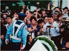  ?? AFP ?? People try to get a glimpse of the wreath laid by US President Obama at the Hiroshima Peace Memorial park cenotaph in Hiroshima, yesterday.