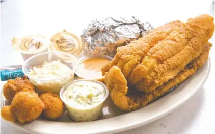  ?? PHOTOS BY MARK GILLILAND ?? A catfish dinner at Riverside Catfish House is served with choice of baked potato or fries, coleslaw, hushpuppie­s or roll.