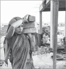  ??  ?? A woman carries bricks at a constructi­on site in New Delhi. So debilitati­ng does the heat get that every 10-15 days, some workers in South Asia have to skip a day of work and lose a day’s pay.
