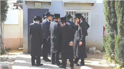  ?? (Hannah McKay/Reuters) ?? ULTRA-ORTHODOX men line up at an IDF draft office in Kiryat Ono yesterday to process their exemptions from mandatory military service.