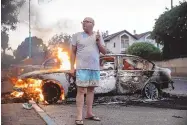  ?? HEIDI LEVINE/ASSOCIATED PRESS ?? Jacob Simona stands by his burning car during clashes between Israeli Arabs and police in the Israeli mixed town of Lod on Tuesday.