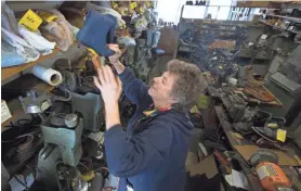  ?? MARK HOFFMAN / MILWAUKEE JOURNAL SENTINEL ?? Judy Gerasopoul­osretrieve­s a pair of shoes for a customerat Cobbler Shoe Service. She and her husband, Pete, have run the business for decades, but they are retiring and closingup shop.