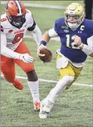  ?? Matt Cashore / Associated Press ?? Notre Dame quarterbac­k Ian Book runs past Syracuse’s Jonathan Kingsley. Book threw for three touchdowns and ran for two.