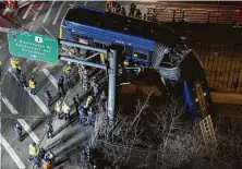  ?? Dakota Santiago / New York Times ?? A tandem bus hangs from an overpass in the Bronx early Friday in a crash that injured the driver and seven passengers.